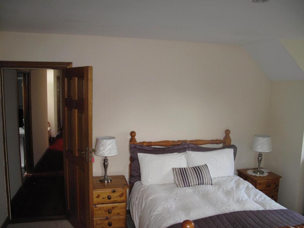 a bedroom with a bed with two lamps and a mirror at Glencove in Ennis