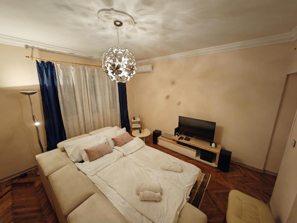 a bedroom with a large white bed and a chandelier at Stadion apartman in Belgrade