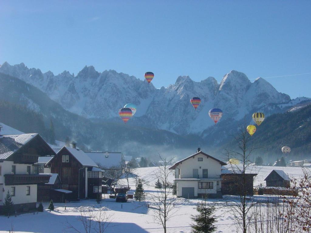 ゴーザウにあるFerienwohnung Lasererの雪に覆われた集落を飛ぶ熱気球