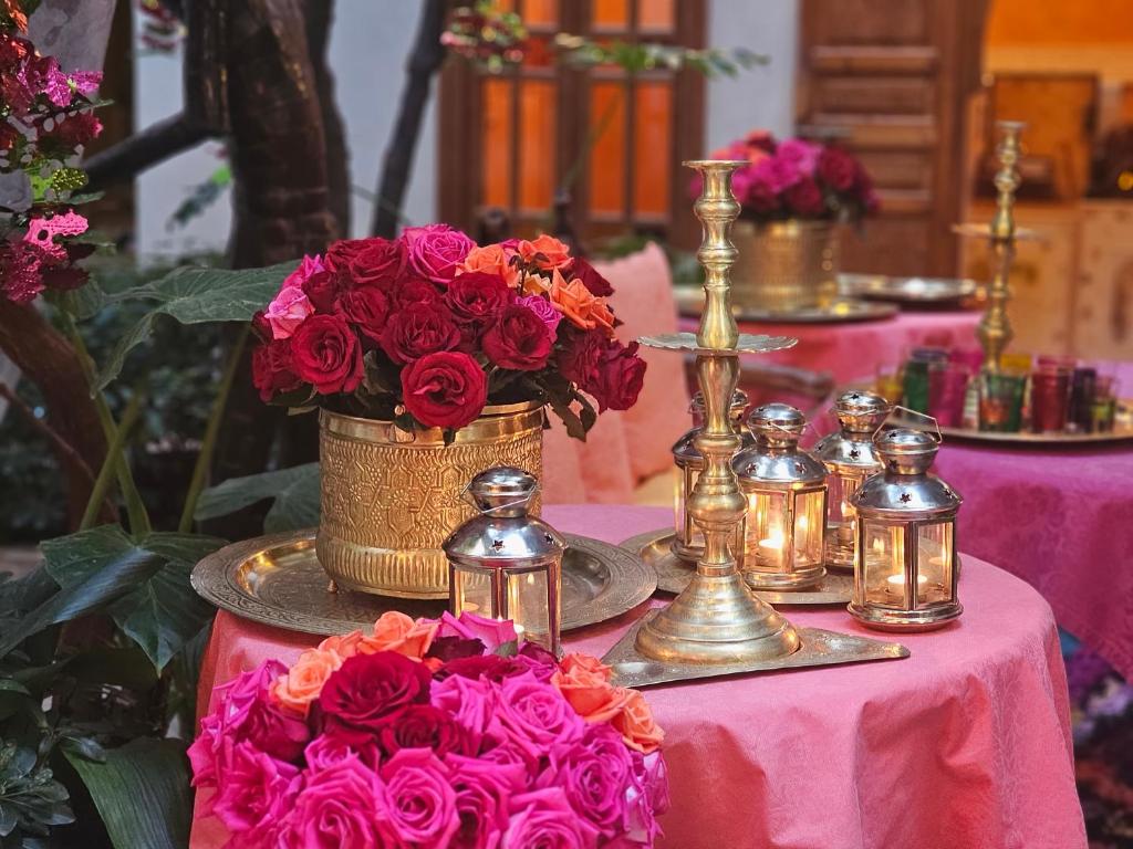a table with a basket of flowers and candles at Riad Jnane d'&Ocirc; in Marrakech