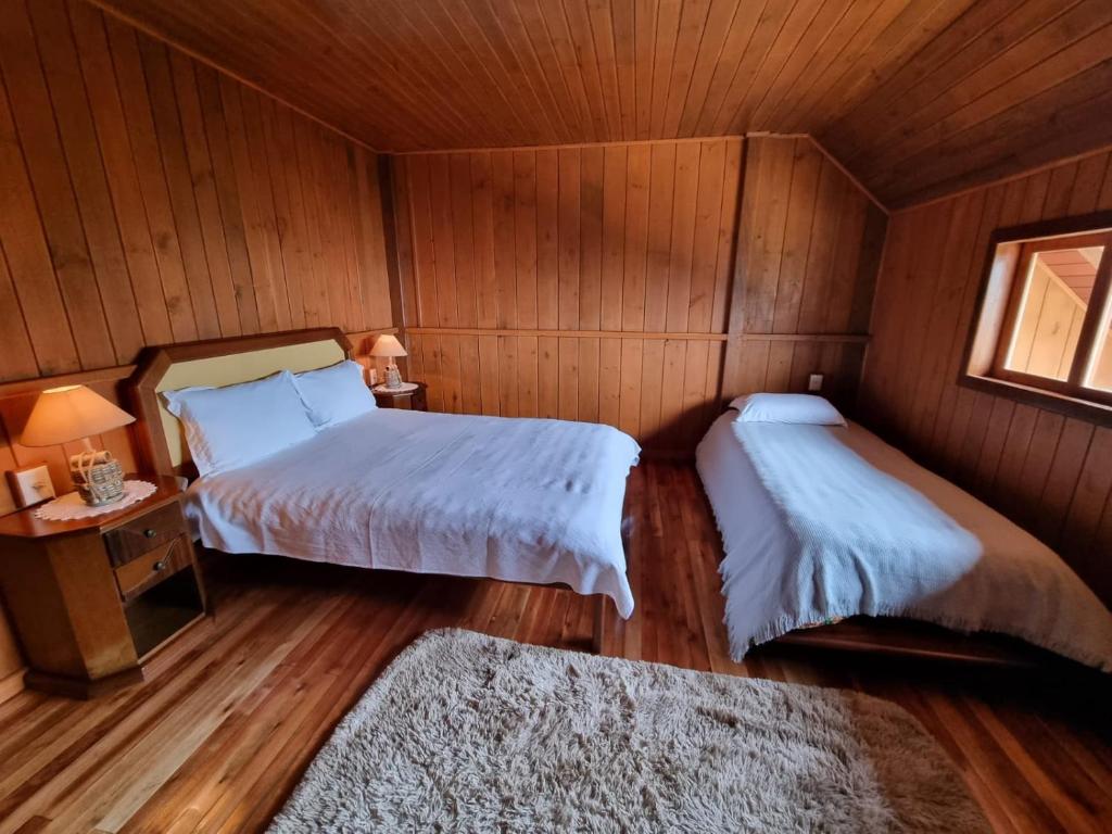a bedroom with two beds and a table and a window at Pousada nevadas da Serra in Urupema