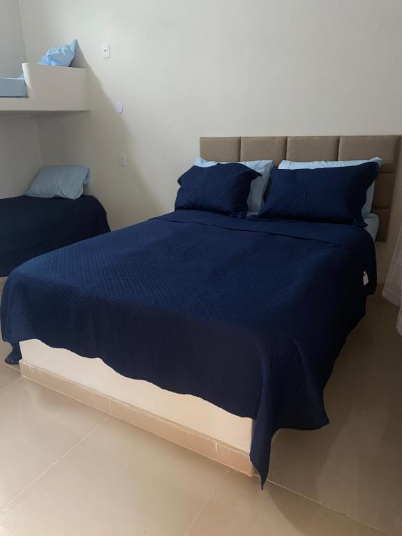 um quarto com uma cama azul com almofadas azuis em Pousada Casa da Praia SFI em São Francisco do Itabapoana