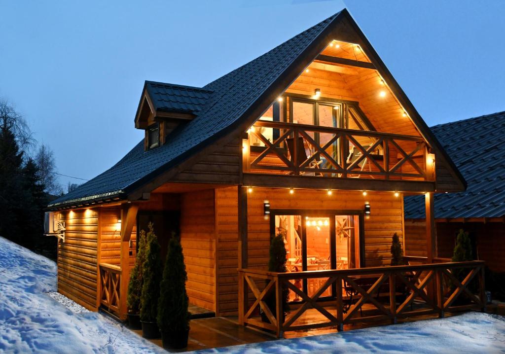 uma cabana de madeira na neve com luzes acesas em Nartorama Domki Zieleniec em Duszniki Zdrój