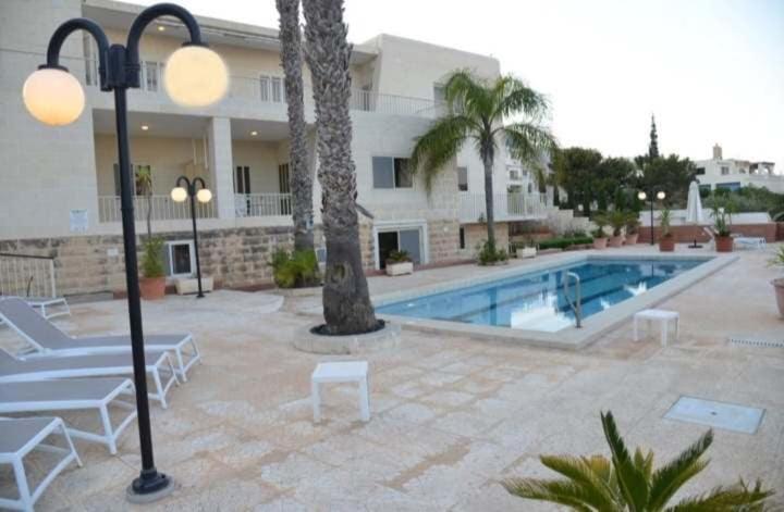 a hotel with a swimming pool and a building at Villa Lyss Apartment 1 in Mellieħa