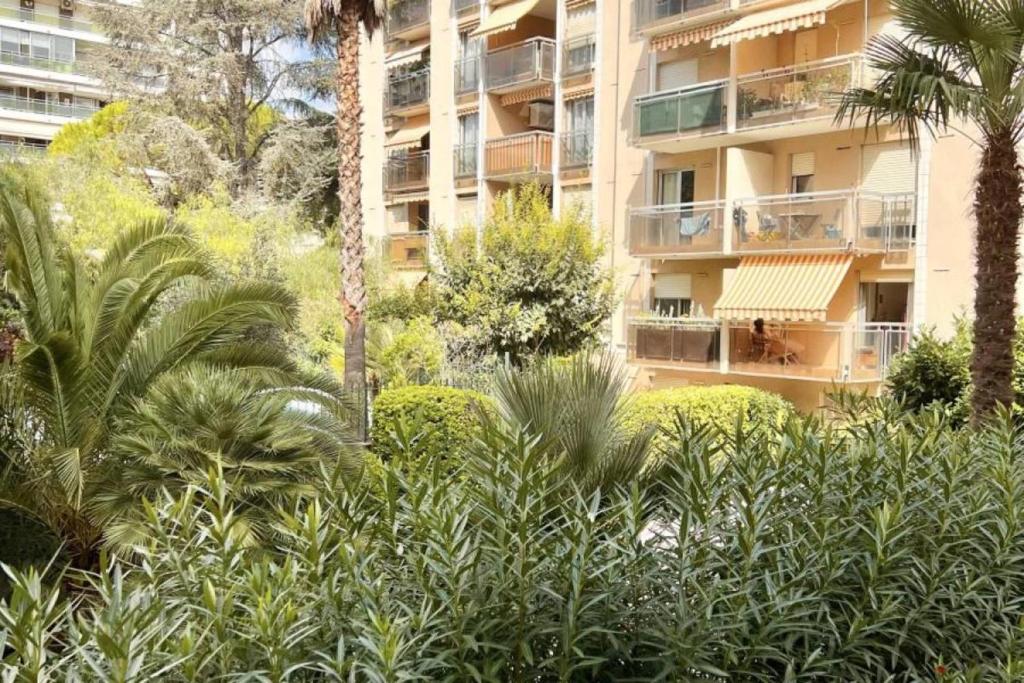 een groot appartementencomplex met palmbomen en struiken bij Charming 49 m love nest in Cannes in Cannes