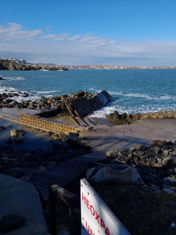 a rocky beach with the ocean and a sign at Созопол Sozopol- SOZOPOLIS - MORE SUN 2В in Sozopol