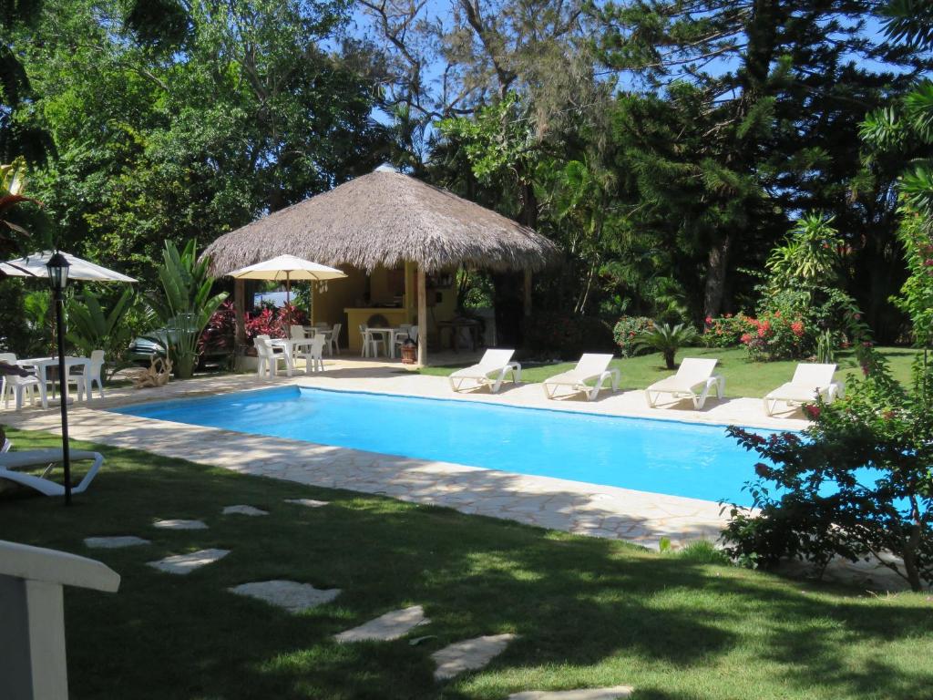 a swimming pool with chairs and a gazebo at Bungalow Natura Village in Sosúa