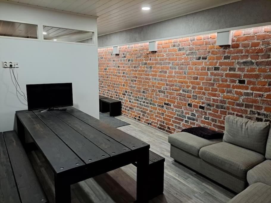 a living room with a table and a couch and a brick wall at Rahkeen majoitus in Joensuu