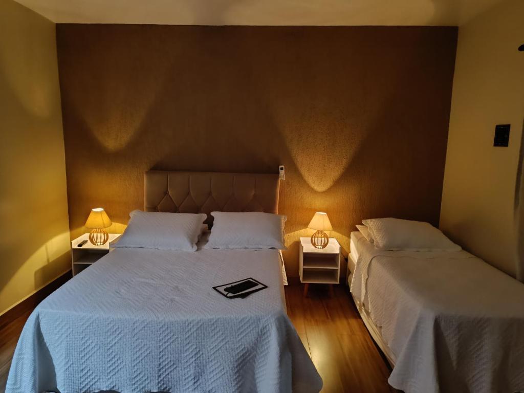 2 camas en una habitación con 2 lámparas en Flat Miguel Pereira, en Miguel Pereira