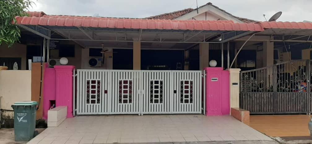 ein Haus mit einem weißen Tor und rosa Türen in der Unterkunft BONDA HOMESTAY in Kampung Gurun