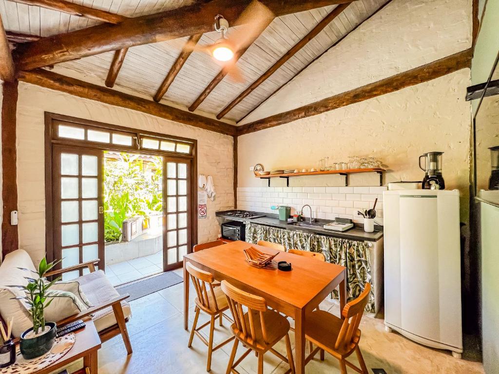 a kitchen with a wooden table and a refrigerator at Patio Camburi - Flat com Piscina à 60m da Praia de Camburi in São Sebastião