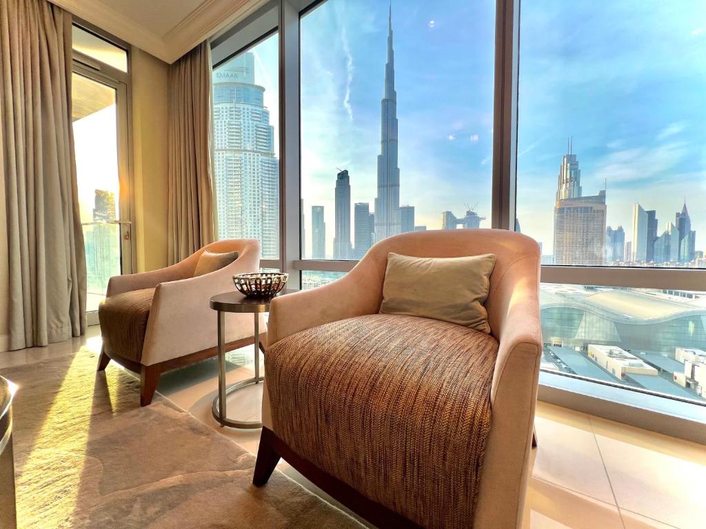 Habitación con 2 sillas y ventana grande. en Downtown Dubai Address Fountain Views Residences - luxurious One Bedroom Apartment, en Dubái