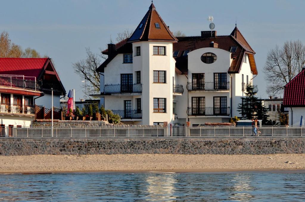 a large white house on the shore of the water at Dom Przy Plaży in Sarbinowo