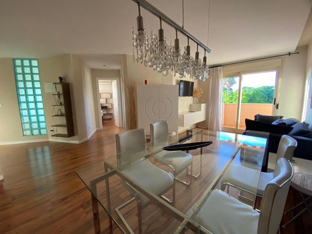 a dining room and living room with a glass table and chairs at Encantador Ático a 2,6 km de la Playa in San Juan de Alicante