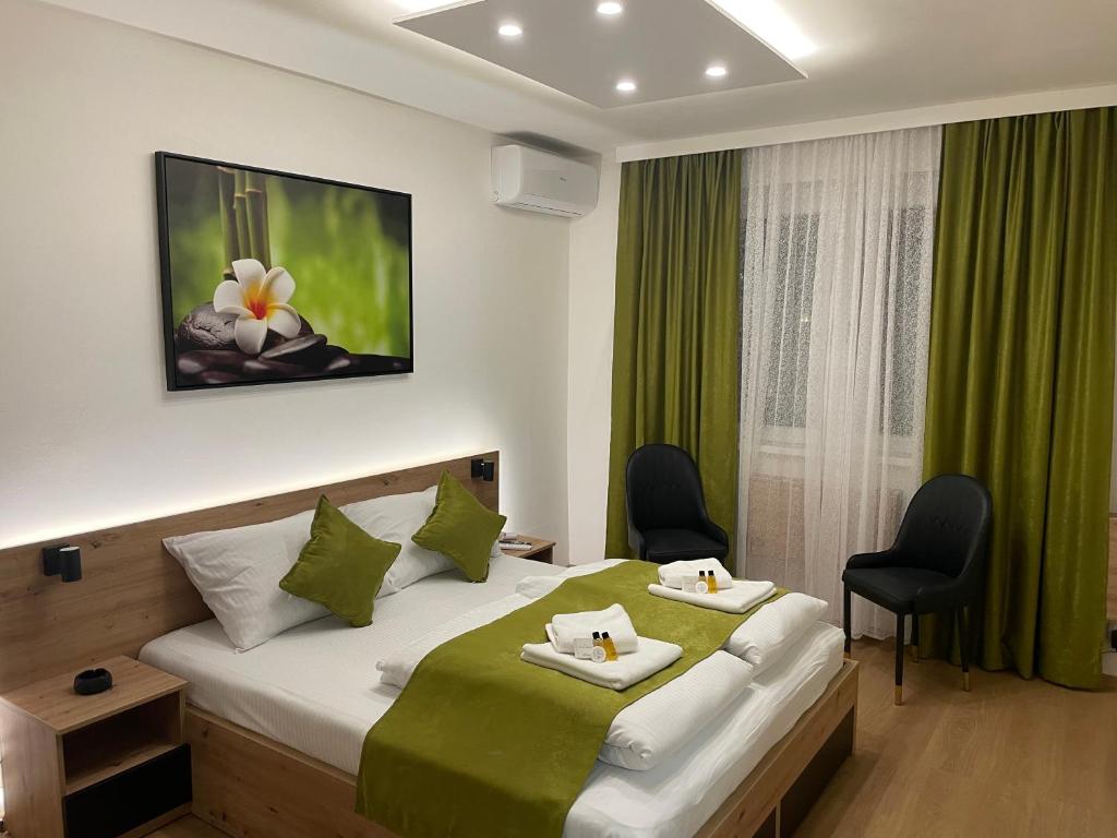 1 dormitorio con 1 cama grande con cortinas y sillas verdes en Inaya Apartman Free Parking, en Sarajevo