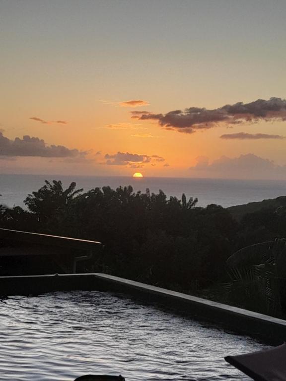 a sunset over the ocean with a swimming pool at Cocon detente a Case pilote, chambre chez l'habitant in Case-Pilote