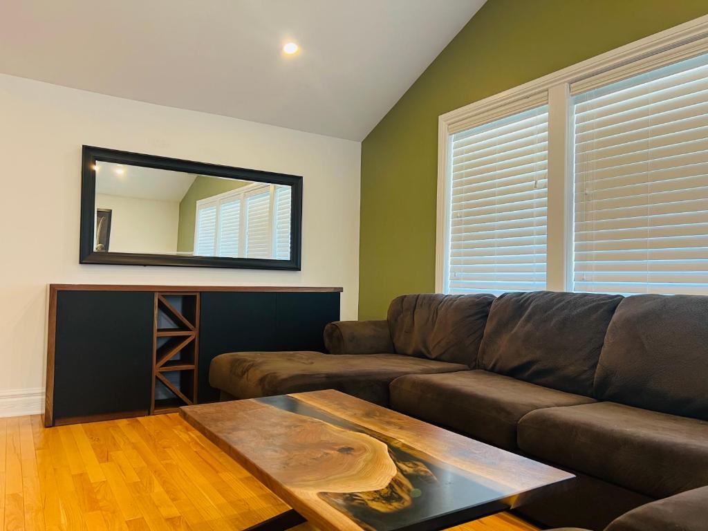 a living room with a brown couch and a mirror at Gorgeous place in Westboro/Hampton Park area in Ottawa