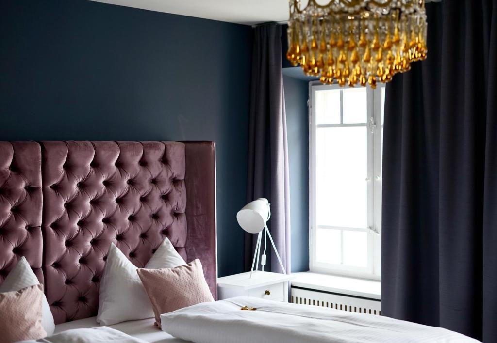 a bedroom with a large headboard and a chandelier at Hotel Mühldorf in Mühldorf