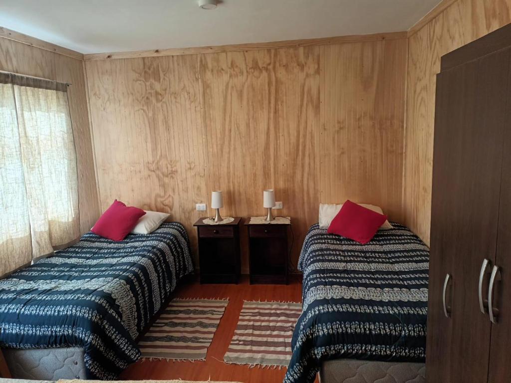 een slaapkamer met twee bedden met rode kussens erop bij Ventisca Sur in Coihaique