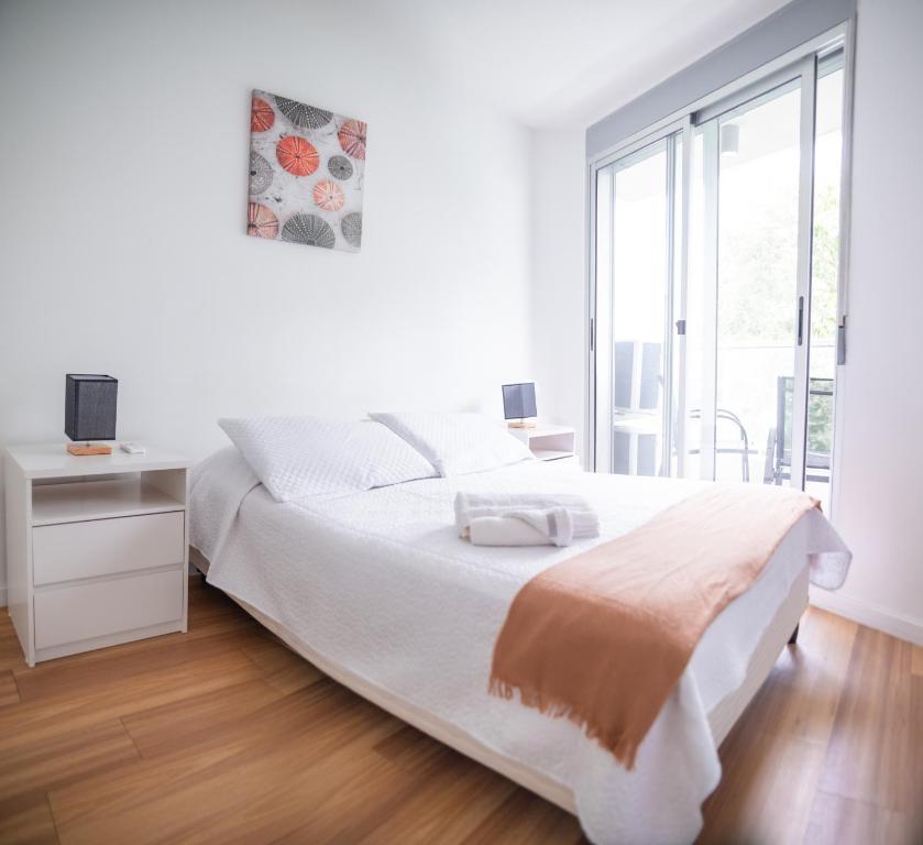 a white bedroom with a large bed and a window at Central y Moderno Apto 1 habitación - Lift Gaucho in Montevideo