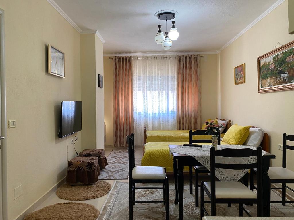 a living room with a table and a bedroom at Apartament pushimi in Pogradec
