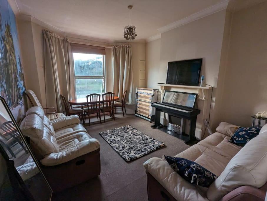 een woonkamer met banken en een televisie en een piano bij Feel Like Your Home in Hastings