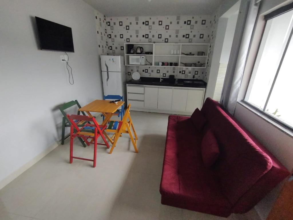 ein Wohnzimmer mit einem roten Sofa und einem Tisch in der Unterkunft Selva Park - Apartamentos completos - próximo ao Beto Carrero e praias in Penha