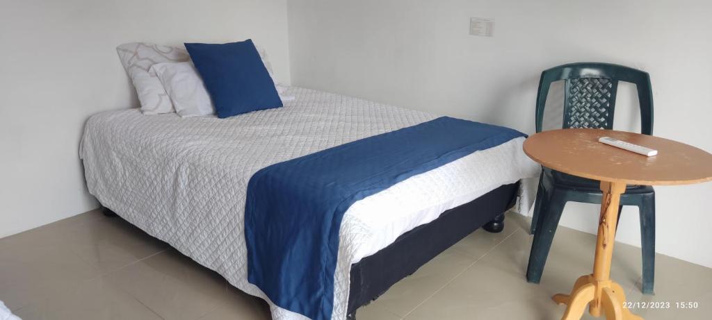 a bedroom with a bed with a table and a chair at HOSPEDAJE DELFIN AZUL in Puerto Villamil