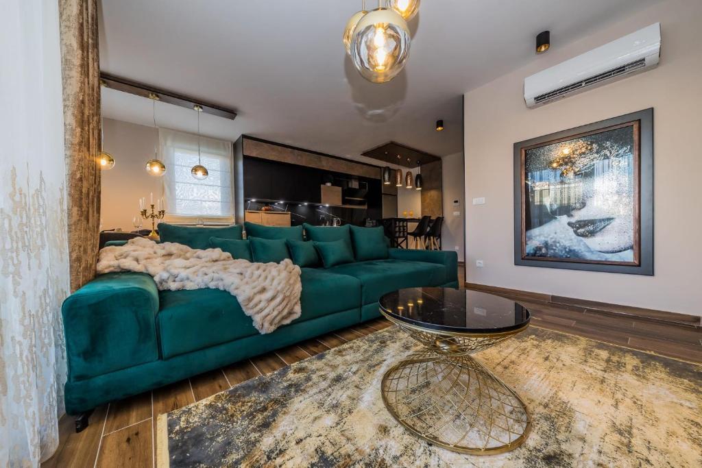 Apartman Bono في سيني: غرفة معيشة مع أريكة خضراء وطاولة