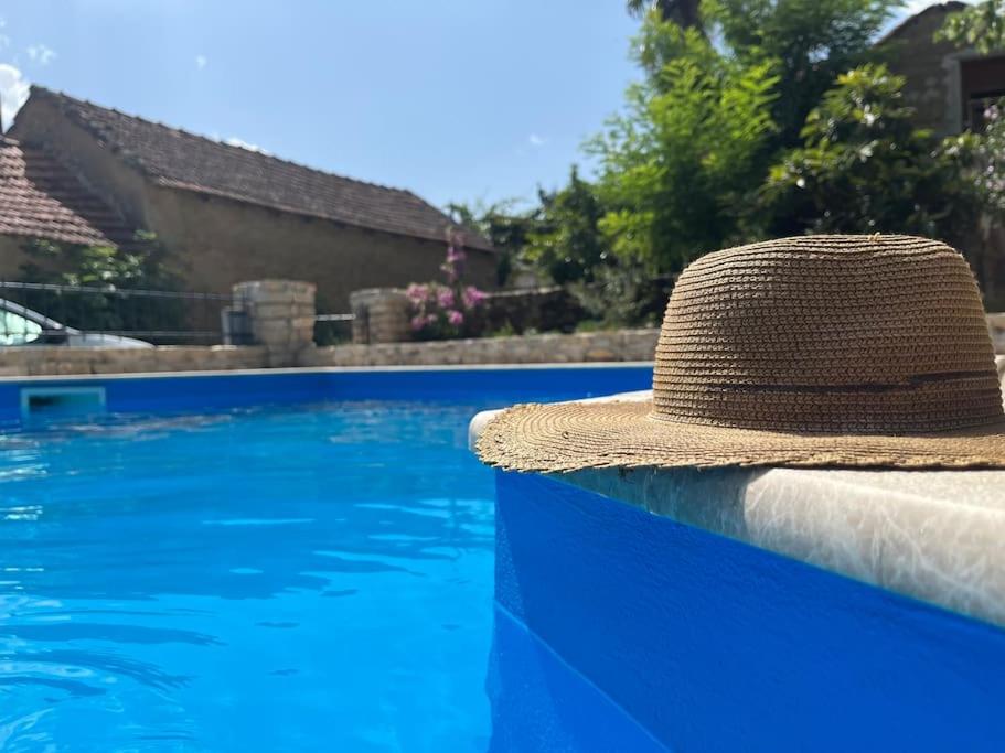 un chapeau en paille assis sur un mur à côté d'une piscine dans l'établissement “House Botić”, 