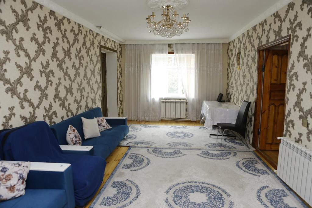 a living room with a blue couch and a chandelier at Gusar house for daily rent in Qusar