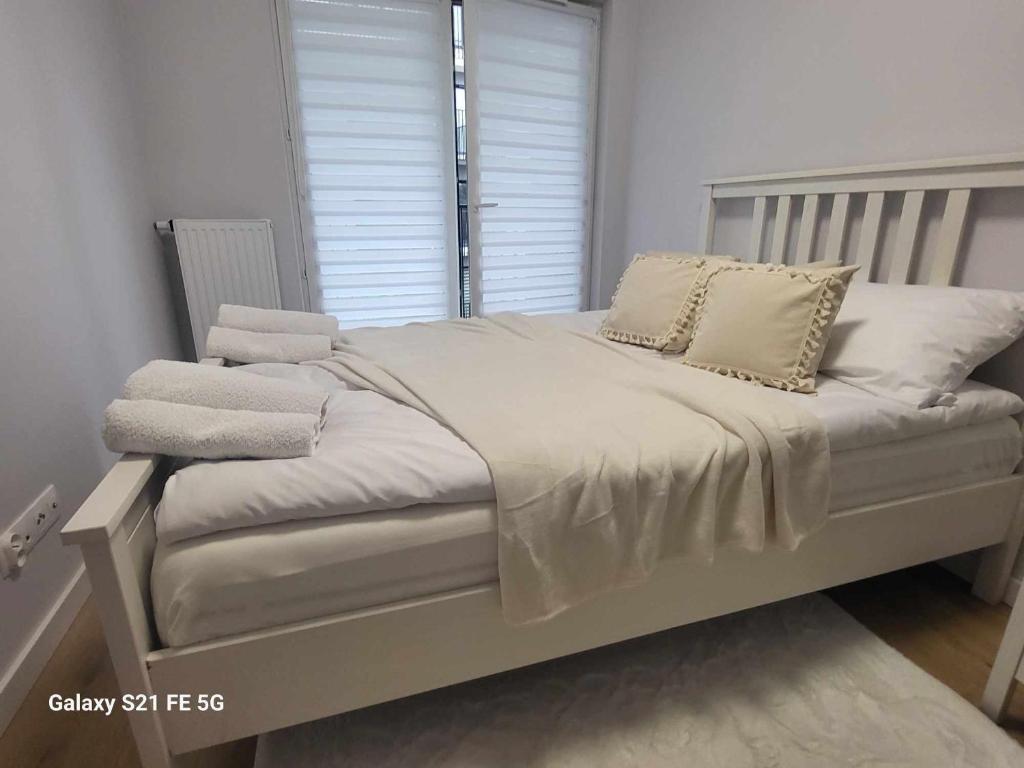 Una cama con sábanas blancas y almohadas en un dormitorio en Blask Księżyca Apartament garaż, en Cracovia