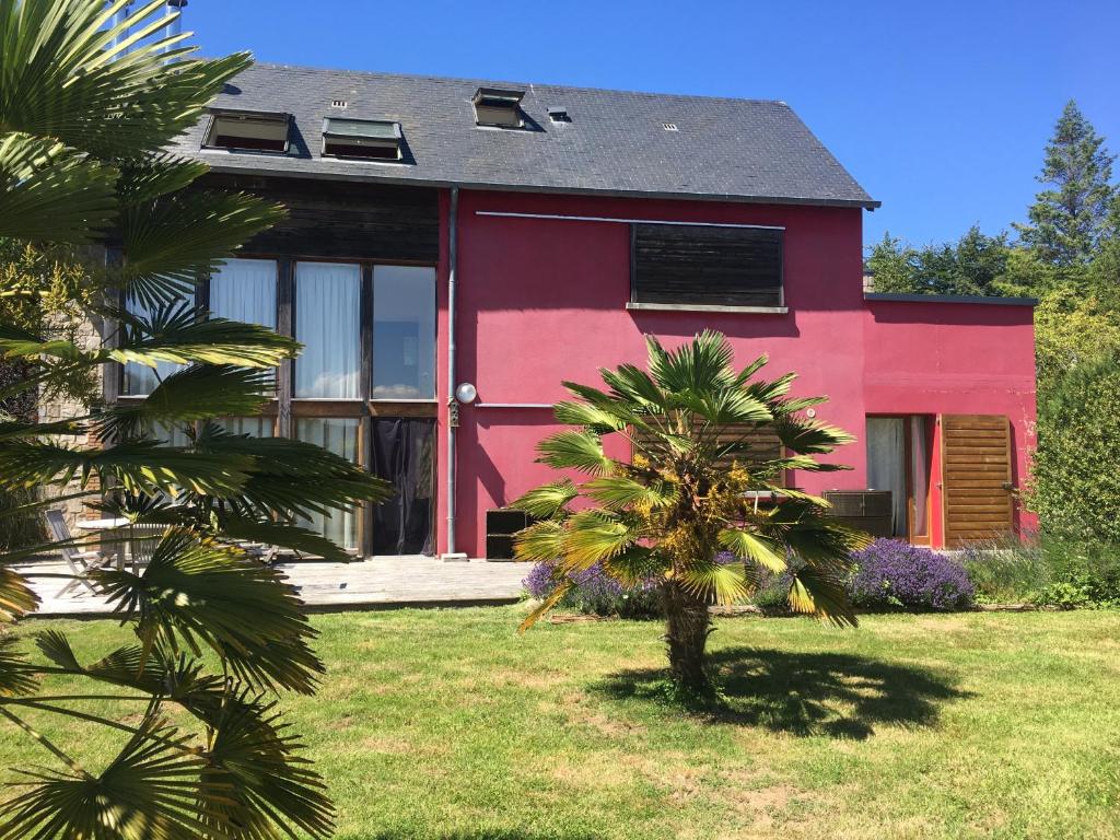 una casa rosa con una palma di fronte di La casa rossa a Saint-Riquier-ès-Plains