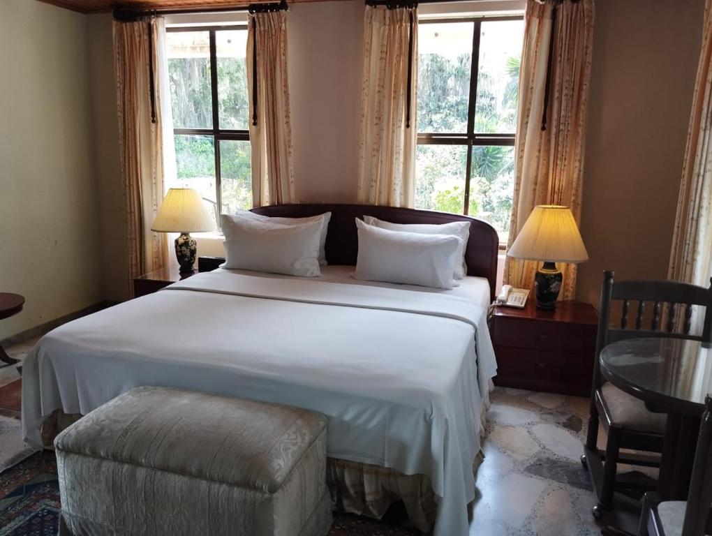 a bedroom with a large white bed with windows at Sunsetfarmhotel in Zipaquirá