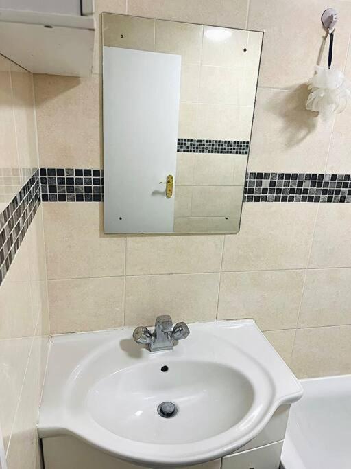 ein Bad mit einem Waschbecken und einem Spiegel in der Unterkunft Room in wembley in London