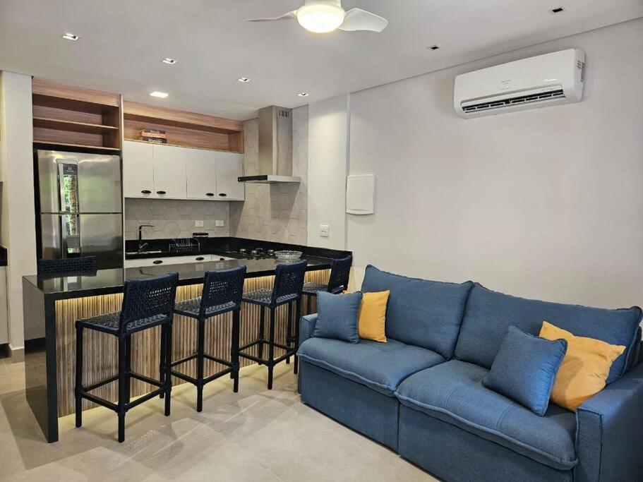 a living room with a blue couch and a kitchen at Flat na Riviera de São Lourenço com serviço de hotelaria in Riviera de São Lourenço