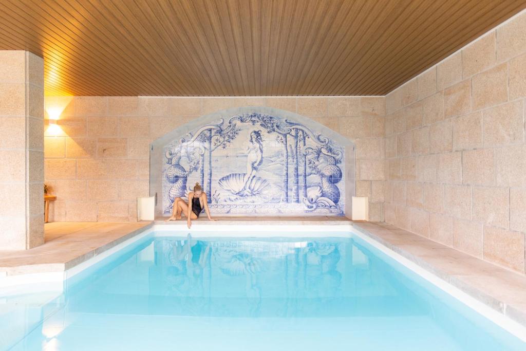 een vrouw zit in een zwembad bij AR Country House in Cadaval