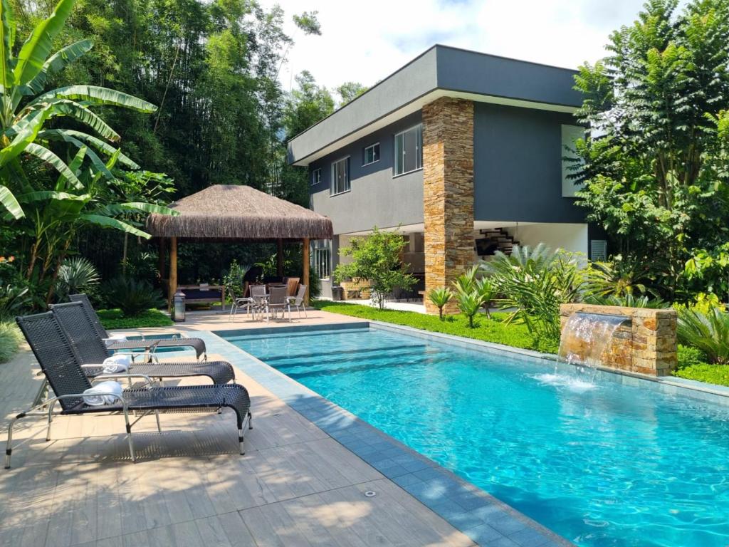 a swimming pool with two lounge chairs next to a house at Paraiso em Angra dos Reis in Angra dos Reis