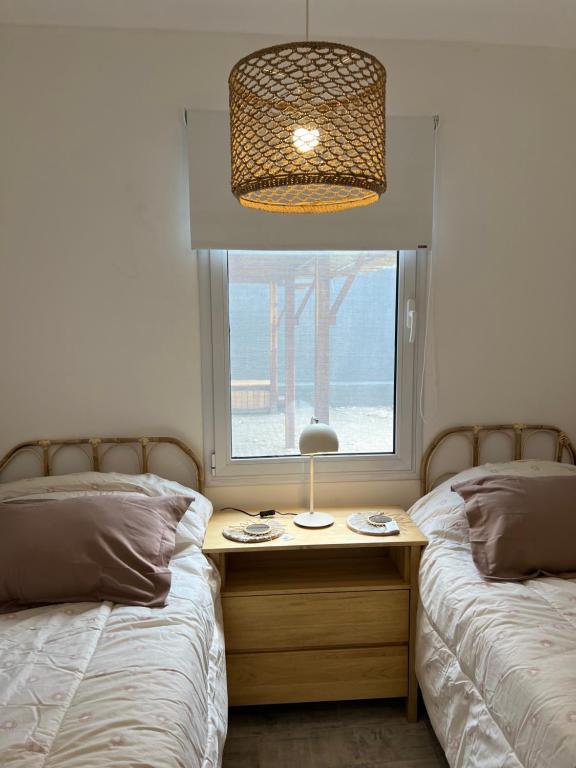 ein Schlafzimmer mit zwei Betten und einem Fenster mit einer Lampe in der Unterkunft Casa de playa y sol in Monte Hermoso