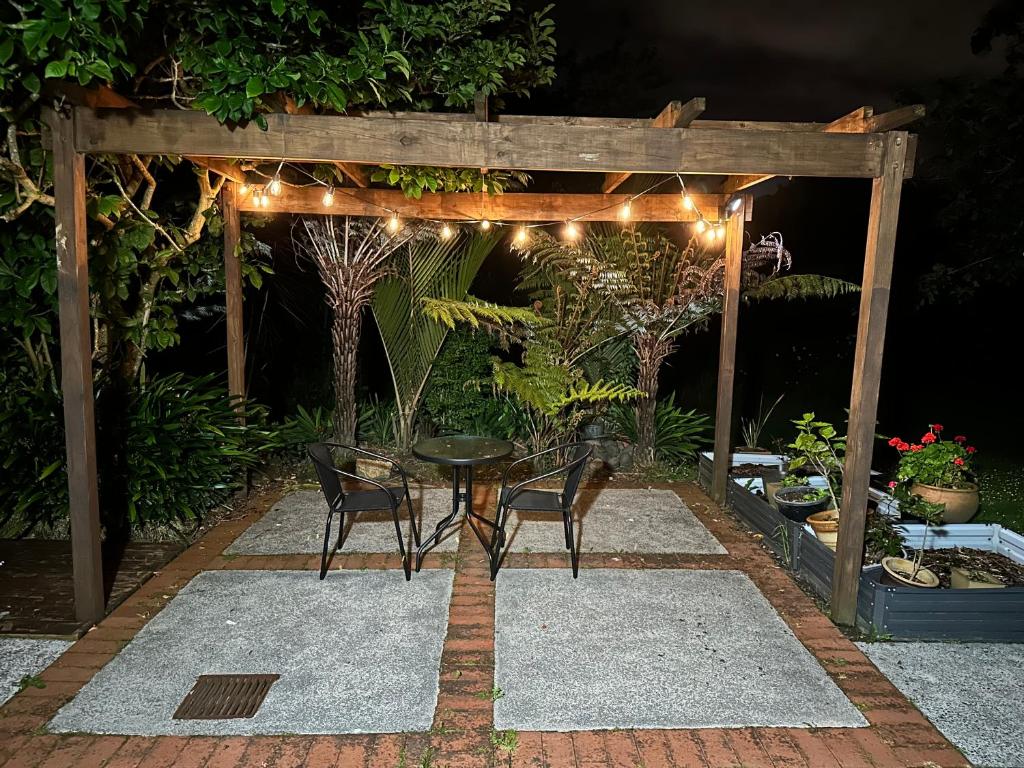 un patio con mesa y sillas bajo una pérgola en New Lynn Self- Contained Unit near Golf Course en Auckland