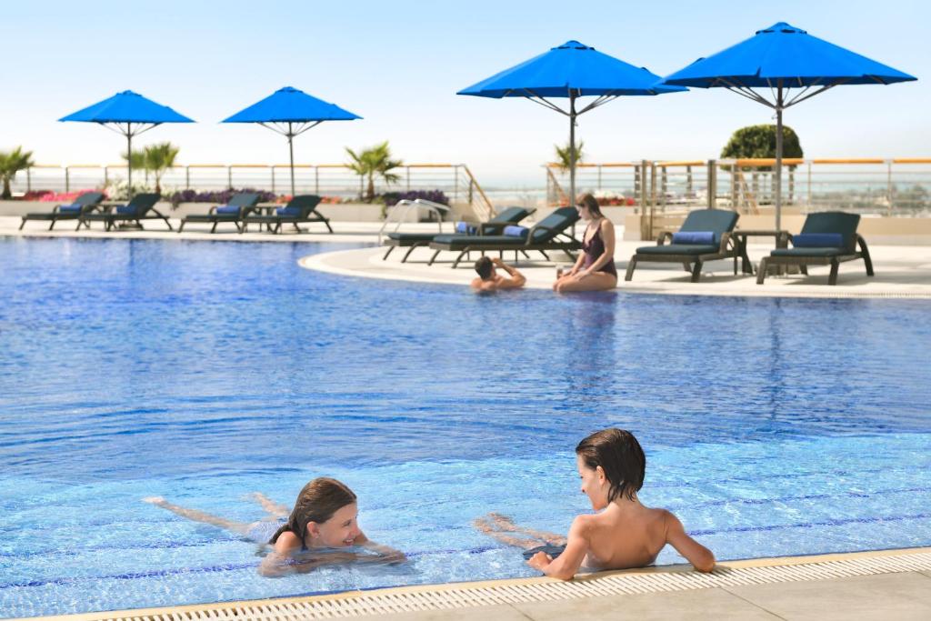 three children playing in the swimming pool at a resort at InterContinental Abu Dhabi, an IHG Hotel in Abu Dhabi