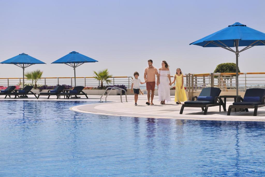 a family walking by the pool at a resort at InterContinental Abu Dhabi, an IHG Hotel in Abu Dhabi