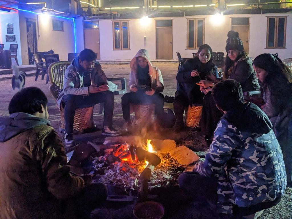 un grupo de personas sentadas alrededor de un fuego en Damnbro Cafe & Stay KASOL, en Kasol
