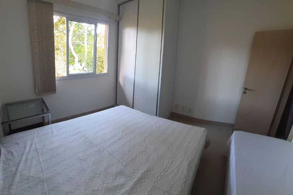 una camera da letto bianca con un letto e una finestra di Casa no Paraíso - Reserva Sapiranga Praia do Forte a Mata de Sao Joao