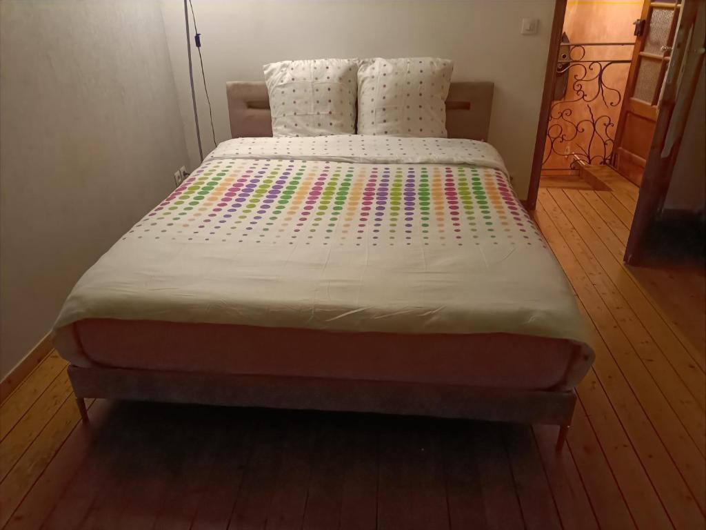 een slaapkamer met een bed met een witte sprei bij Maison sur 3 étages, proche de Disneyland in Jouarre