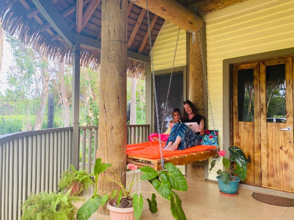 a woman and a child sitting on a porch at Fale Tonga Guesthouse in Puke