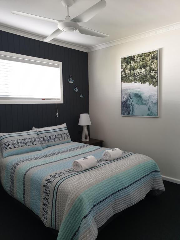 1 dormitorio con 1 cama y ventilador de techo en Lisianna Apartments en Hervey Bay