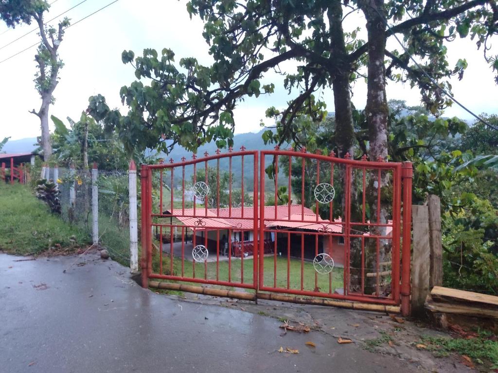 un portail rouge devant un arbre dans l'établissement Villa Lucy, à Charalá