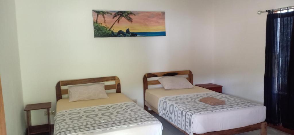Zimmer mit 2 Betten und Wandgemälde in der Unterkunft Dewi Garden Guesthouse in Kuta Lombok