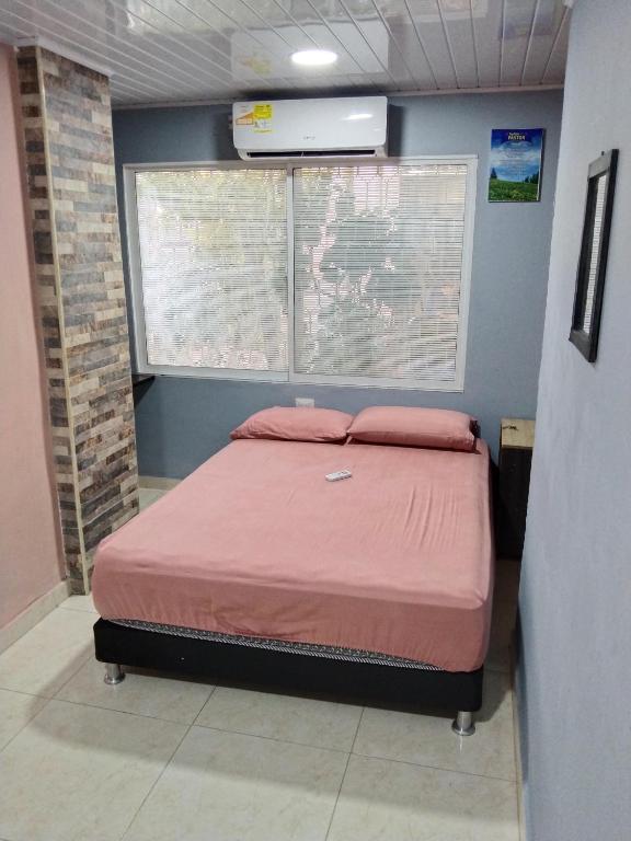 um quarto com uma cama com lençóis cor-de-rosa e uma janela em SANTA MARTA - RIASCOS em Santa Marta